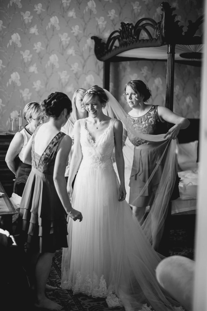 Bridesmaids helping to dress Bride on her wedding day at Huntsham Court Devon