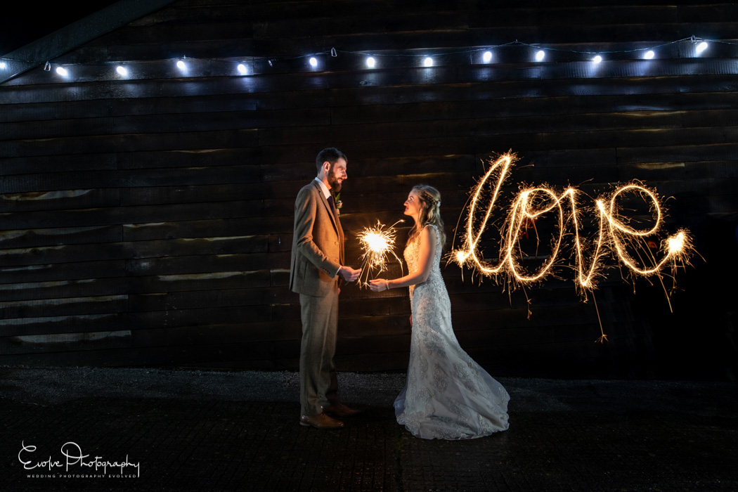 Bride and Groom with sparklers spelling LOVE at The Green in Cornwall Wedding